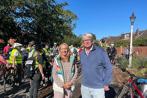 Councillors Sarah Osborne and Paul Mellor with a large group of cyclists. The cyclist are all in safety gear and two of them have "Marshal" signs on their kit.