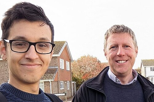 Head and shoulders of Freddie Hoareau and James MacCleary with a suburban background of houses and trees.