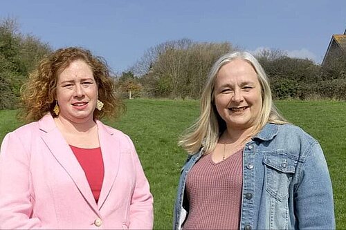 Christina Bristow and Lesley Boniface standing in sunshine against a background of grass and sky at Valley Dip in Seaford