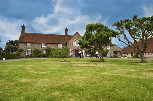 old style school buildings seen across an expanse of grass and trees