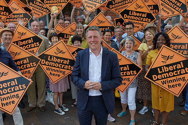 James MacCleary in front of a forest of LibDem diamond posters held by some very happy looking members