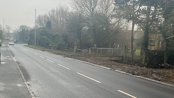 Avis Road on a wet day showing pavement on one side, mud on the other and some drainage apparently in need of upkeep