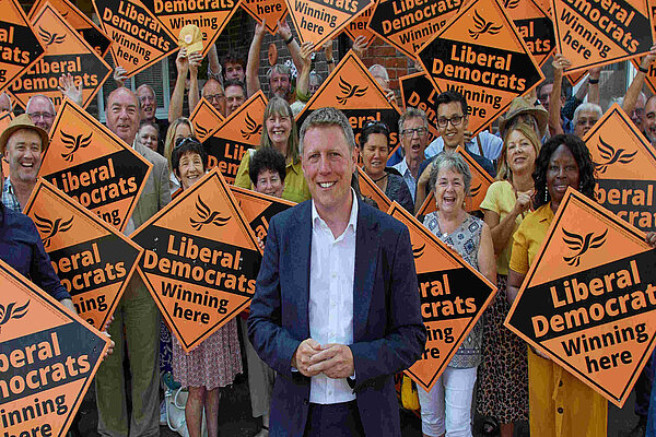 James MacCleary in front of a forest of LibDem diamond posters held by some very happy looking members