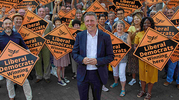 James MacCleary in front of a forest of LibDem diamond posters held by some very happy looking members