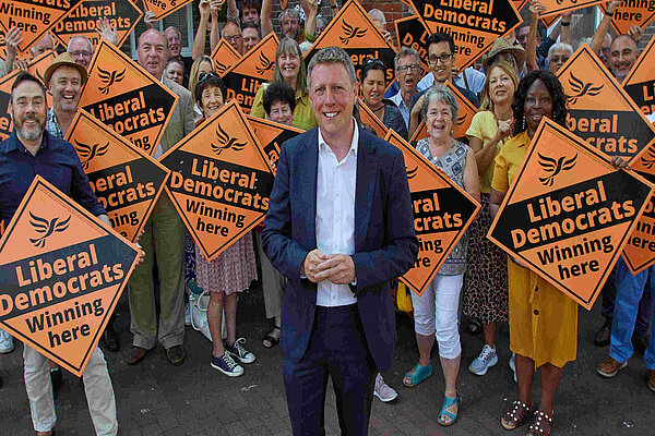 James MacCleary in front of a forest of LibDem diamond posters held by some very happy looking members