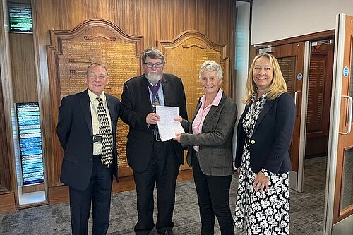 Councillor Sarah Osborne and residents hand in their petition in front of an ornately carved honours list.