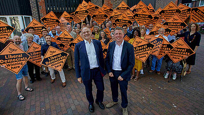 James MacCleary and Ed Davey both looking very happy  in front of a sea of LibDem diamond posters