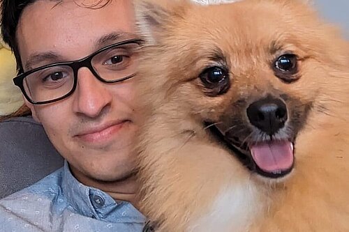 Penny, a medium sized long haired terrier type dog with a pointed nose, dark eyes and an energetic expression, with Councillor Freddie Hoareau